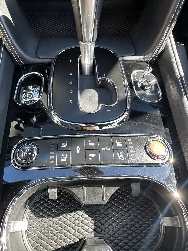 Gros plan sur la console centrale noire de la Bentley Continental GT Speed 2015 avec levier de vitesses automatique et boutons de contrôle.