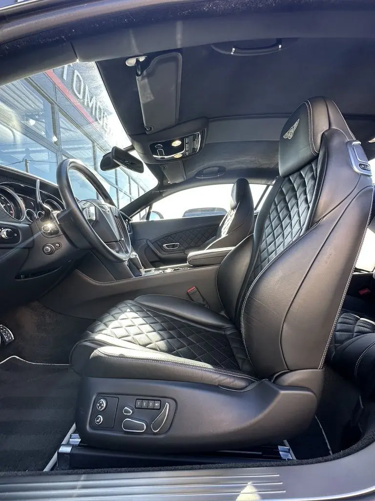 Intérieur noir de la Bentley Continental GT Speed 2015 vu côté conducteur, sièges en cuir matelassé avec logo brodé.