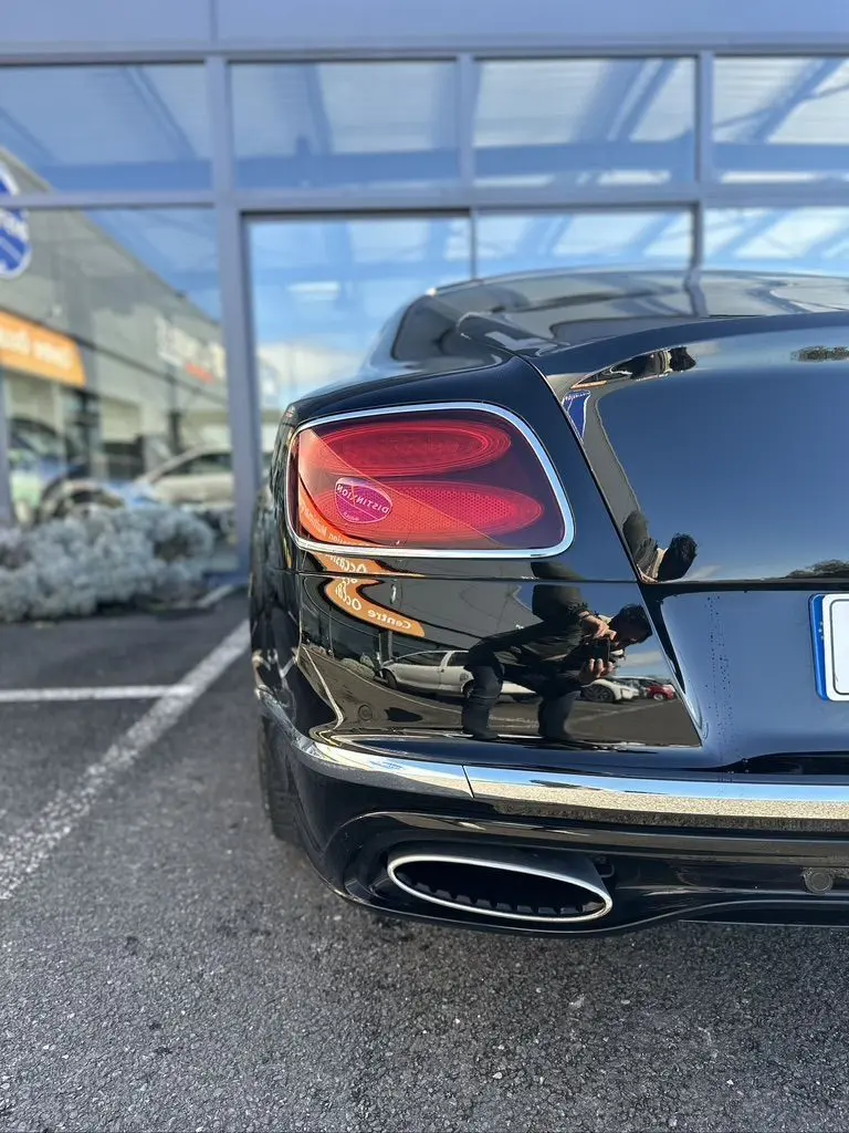 Vue arrière côté gauche d'une Bentley Continental GT Speed noire de 2015 avec feu arrière distinctif et sortie d'échappement ovale chrome.