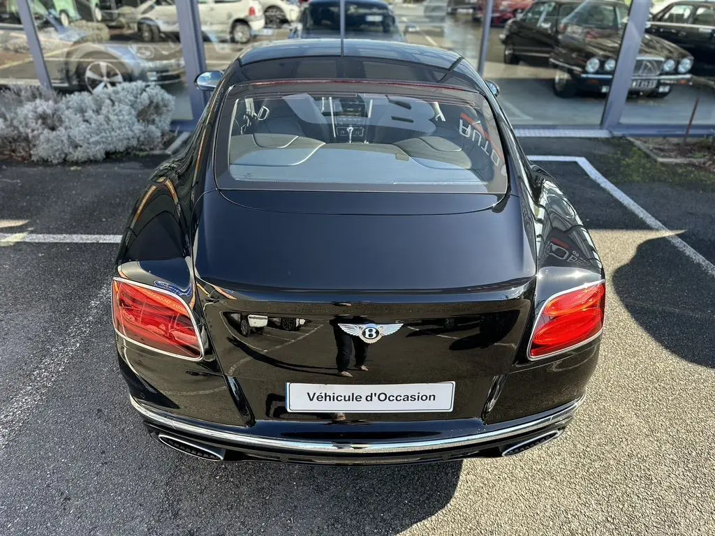 Vue arrière d'une Bentley Continental GT Speed noire de 2015 avec feux rouges et double sortie d'échappement chromée.