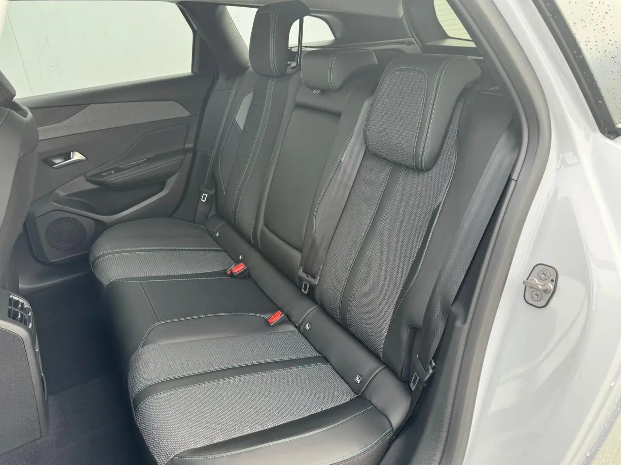 Vue côté gauche de la banquette arrière en sellerie TEP/tissu noir avec surpiqûres bleues du Peugeot 308 SW blanc Okenite 2024.