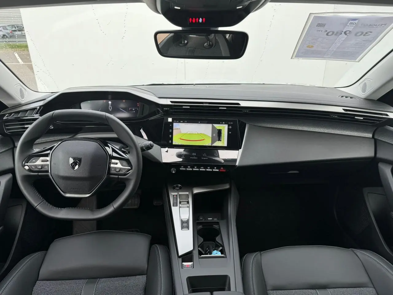 Intérieur avant du Peugeot 308 SW 2024, tableau de bord noir avec écran tactile et volant compact au design moderne.