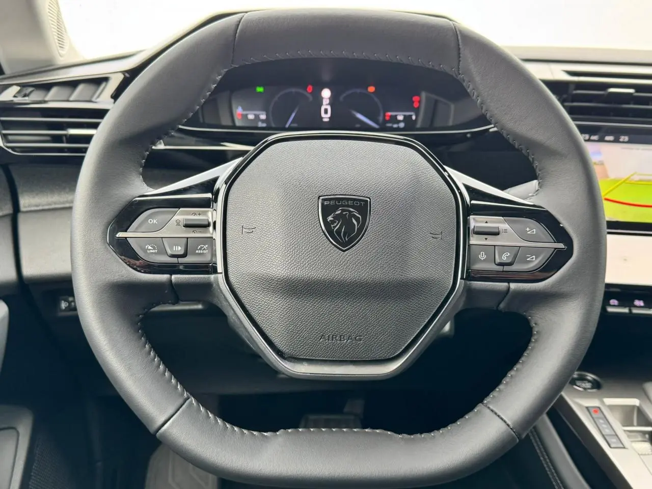 Volant cuir noir au design hexagonal du Peugeot 308 SW 2024 avec commandes intégrées et tableau de bord numérique visible.