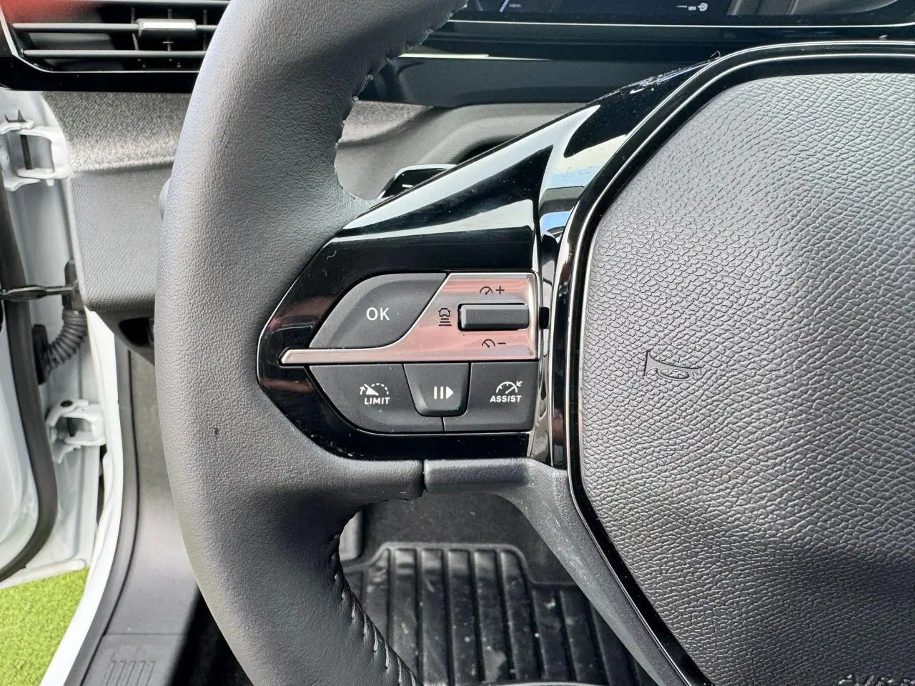 Gros plan sur le volant noir du Peugeot 308 SW 2024, montrant les commandes de régulateur et assistant de conduite.