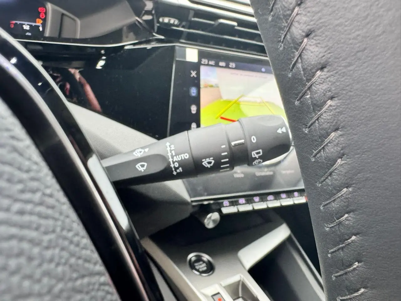 Gros plan sur la commande d'essuie-glace et l'écran tactile affichant la caméra de recul dans l'habitacle du Peugeot 308 SW blanc.