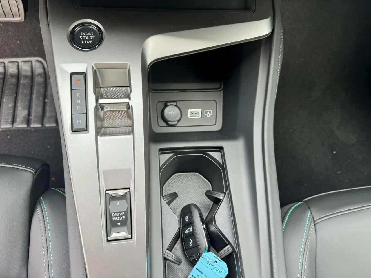 Gros plan sur la console centrale grise avec bouton start, levier de vitesses électronique et clé PEUGEOT 308 SW blanche.