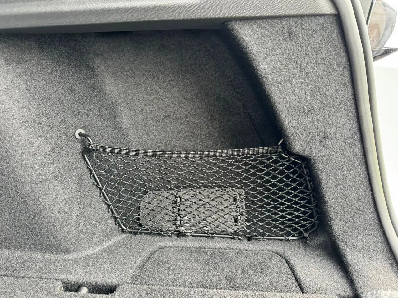 Filet de rangement noir fixé dans le coffre du Peugeot 308 SW blanc Okenite, vue intérieure côté droit.