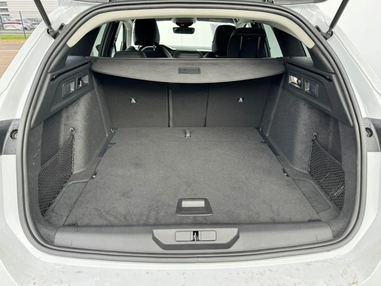 Coffre ouvert d'une Peugeot 308 SW blanche, vue arrière montrant un espace de chargement spacieux et bien agencé.