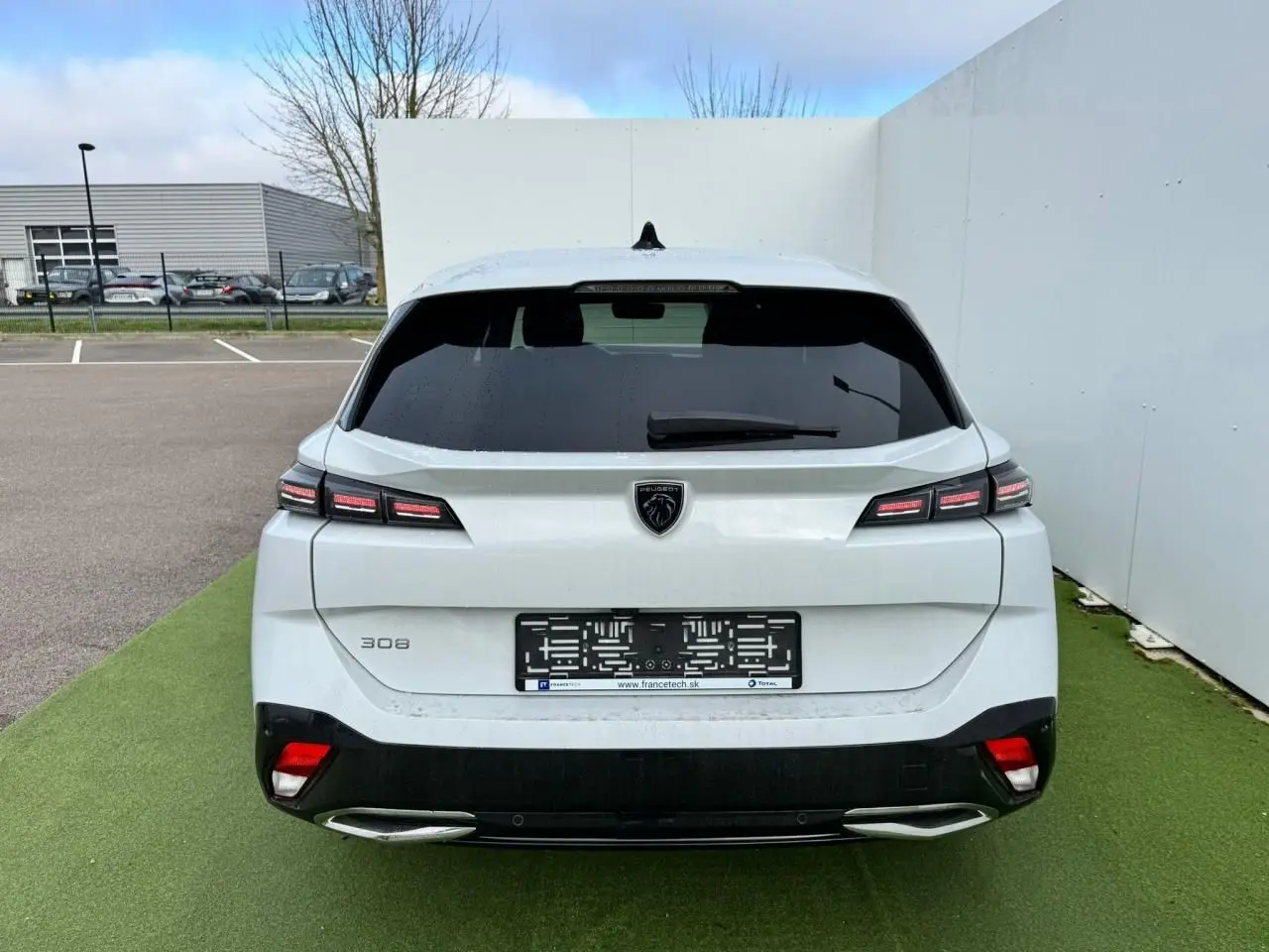 Vue arrière d'une Peugeot 308 SW blanche Okenite avec feux LED distinctifs et double sortie d'échappement chromée.