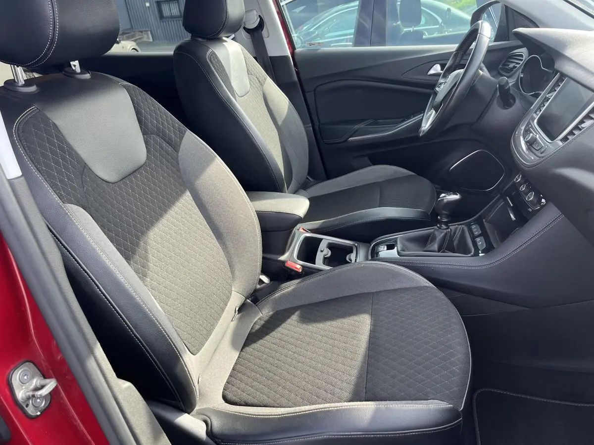 Intérieur avant de l'Opel Grandland rouge, vue côté gauche sur sièges tissu noir et console centrale avec levier manuel.
