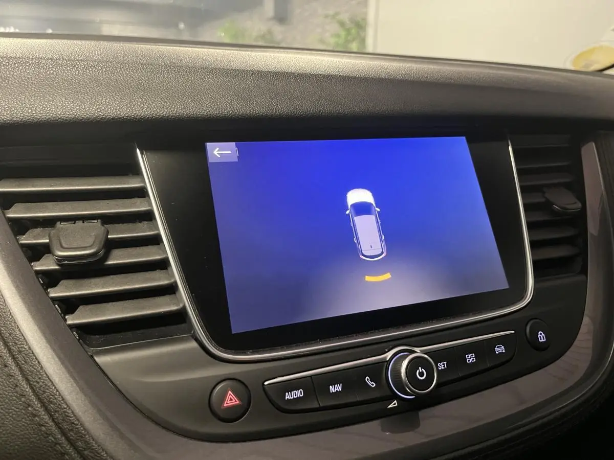 Écran tactile central du tableau de bord de l'Opel Grandland rouge, affichant l'aide au stationnement.