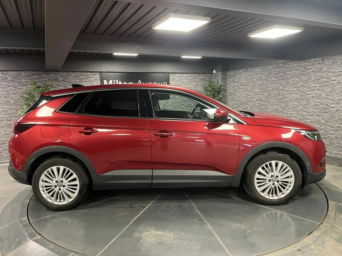 Opel Grandland rouge métallisé vu de profil côté gauche dans un showroom avec jantes alliage 18 pouces.
