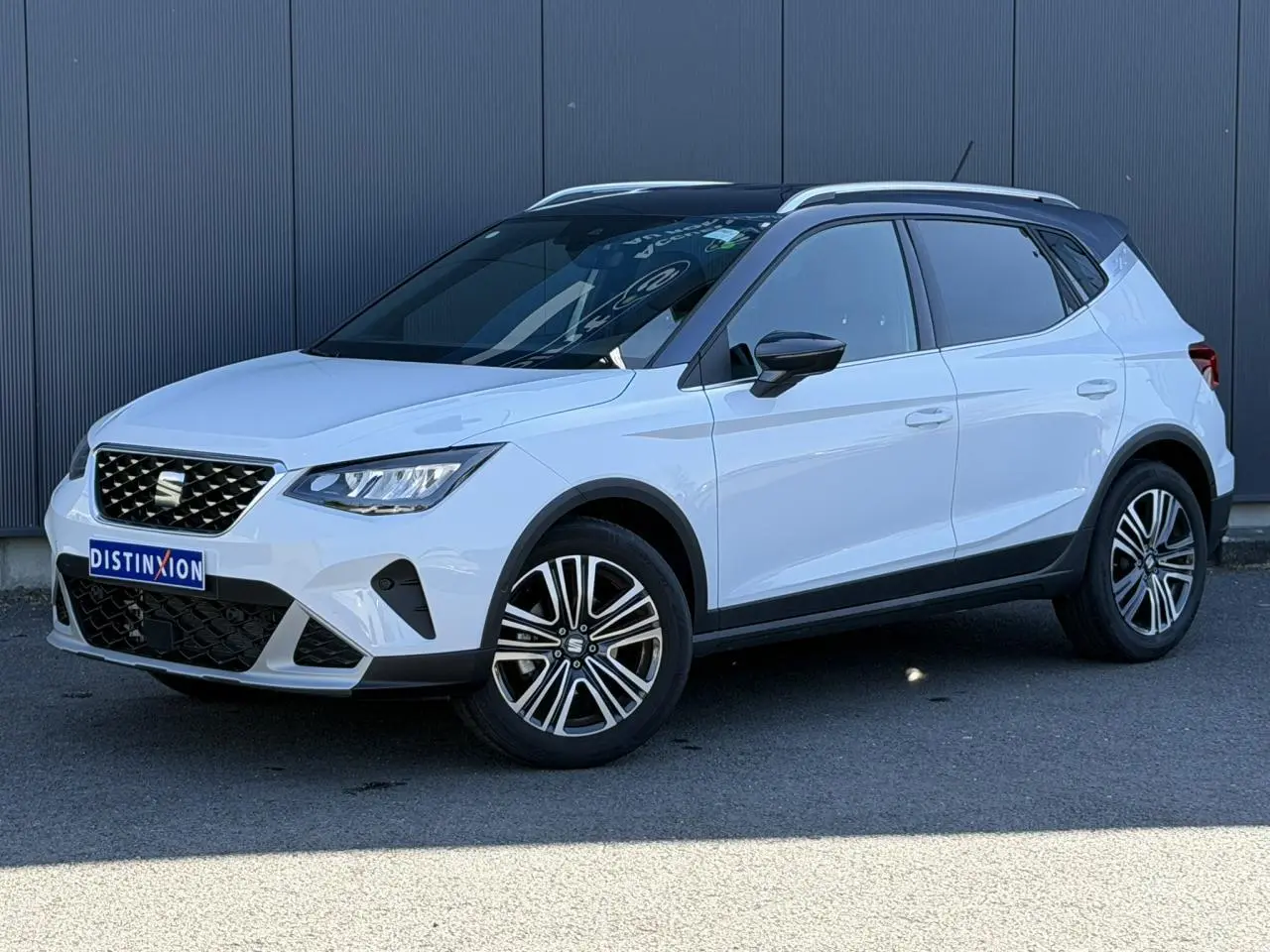 SEAT Arona blanc Nevada avec toit noir, vue 3/4 avant droit, jantes alliage 17 pouces et calandre chromée.