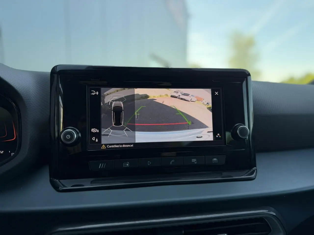 Écran central montrant la caméra de recul et l’aide au stationnement du SEAT Arona blanc Nevada, vue intérieure.
