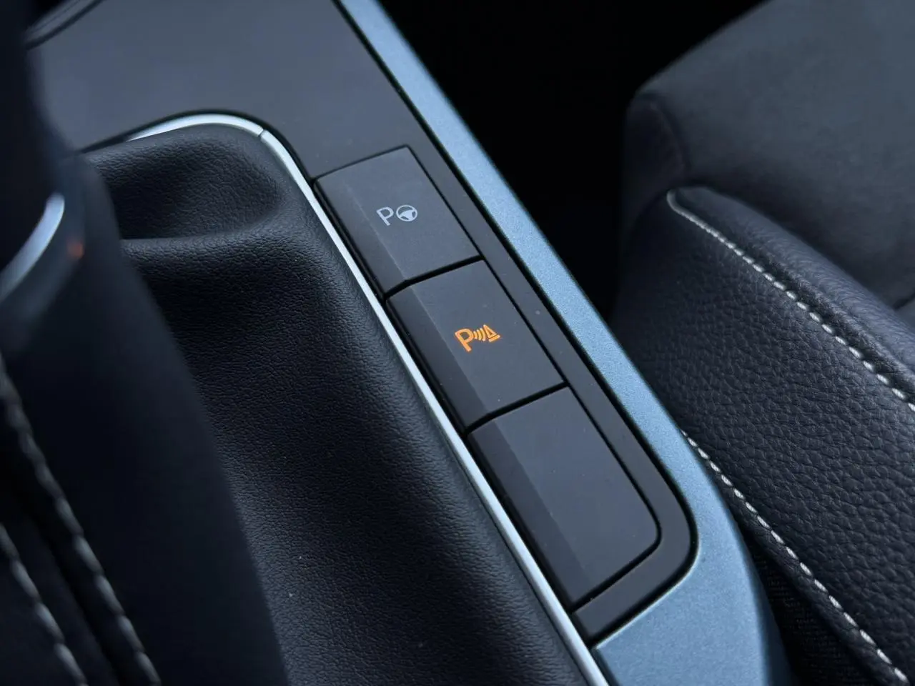 Gros plan sur les boutons d’assistance au stationnement dans l’habitacle noir du SEAT Arona TSI 115 Xpérience.