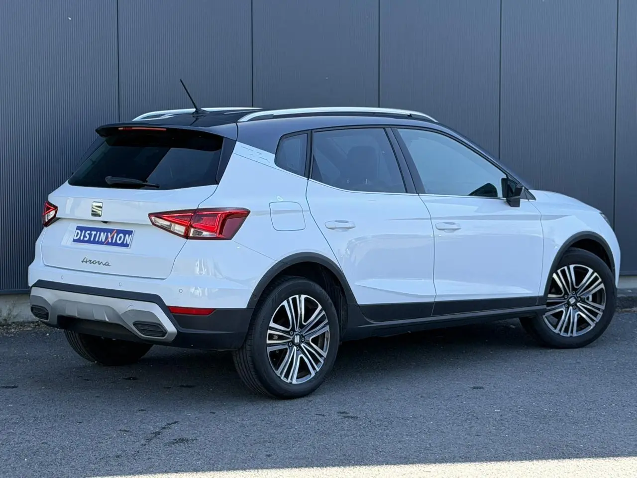 Vue 3/4 arrière droite du SEAT Arona blanc Nevada avec toit noir et jantes alliage 17 pouces, arrière surteinté.