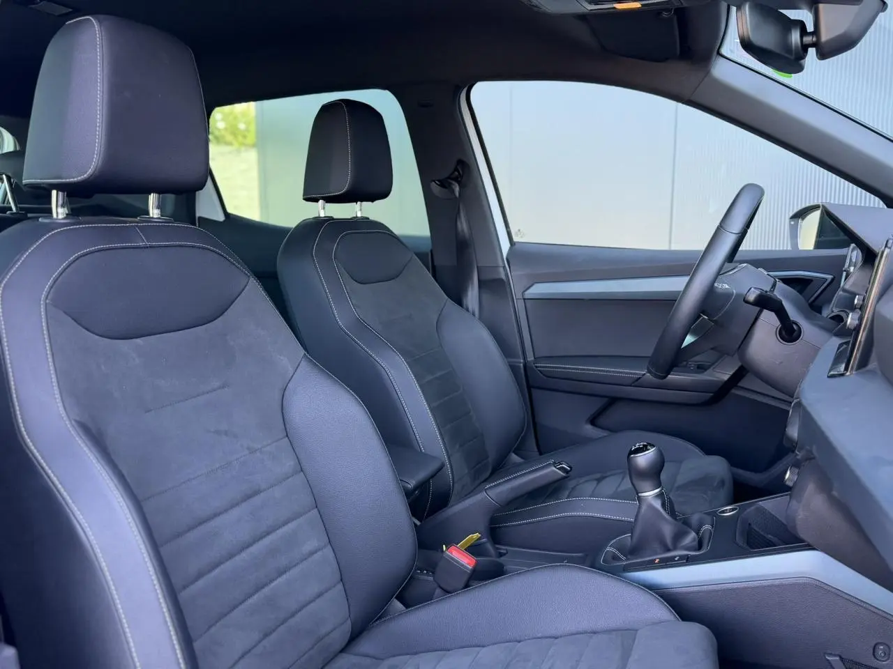 Intérieur côté conducteur du SEAT Arona TSI 115 Xpérience 2025, sièges cuir-alcantara noirs avec surpiqûres blanches.