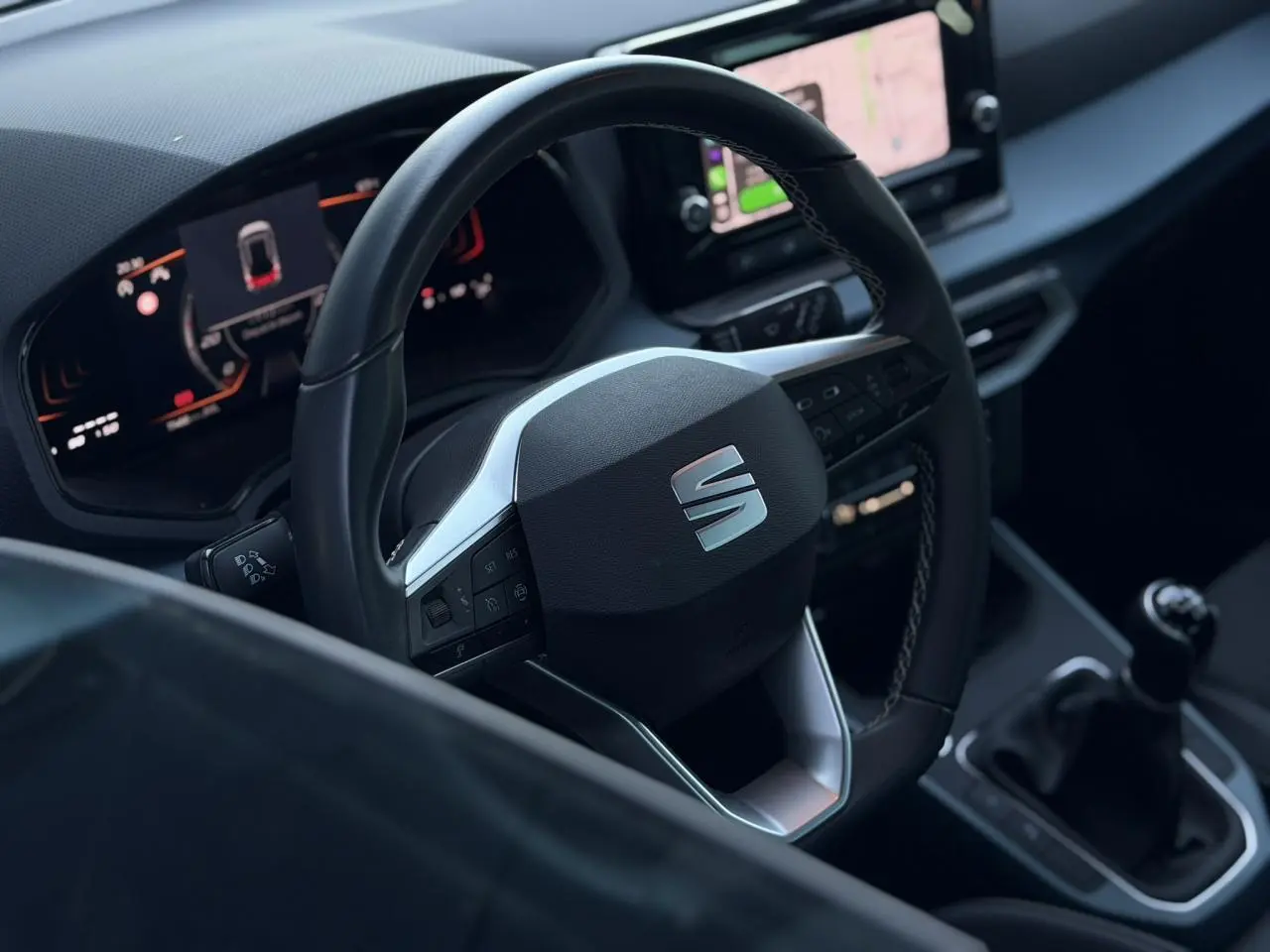 Vue intérieure centrée sur le volant multifonction de la SEAT Arona avec tableau de bord digital et levier de vitesse manuel.