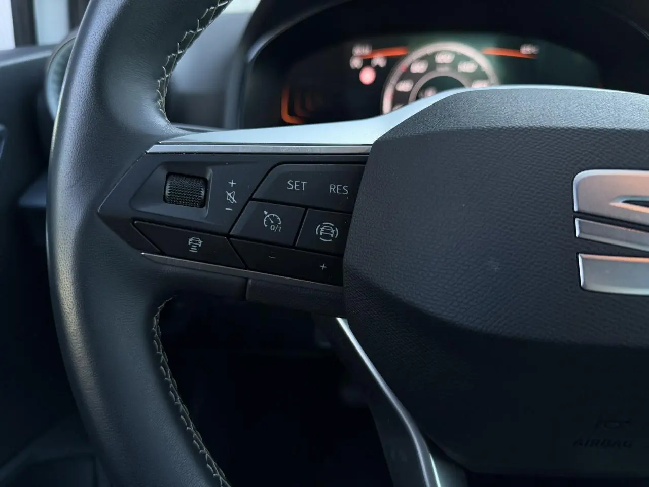 Gros plan sur la partie gauche du volant noir de la SEAT Arona 2025 avec commandes de régulateur et aide à la conduite.