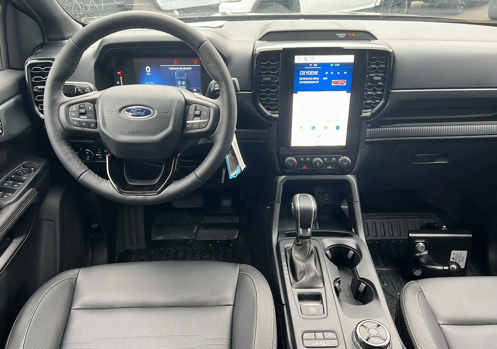 Vue intérieure avant du Ford Ranger 2025 avec volant cuir multifonctions et écran tactile vertical.