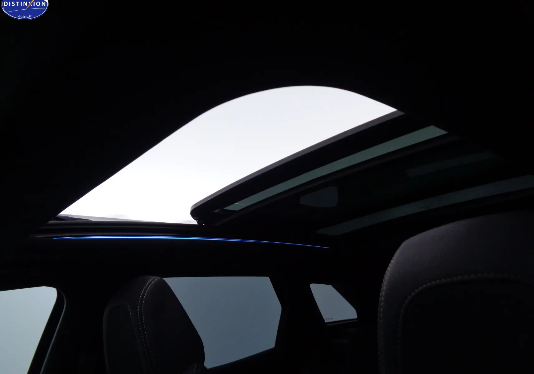 Toit panoramique ouvert sur l'intérieur noir du Peugeot 3008 GT 2023, mettant en valeur les sièges en cuir et l'ambiance lumineuse.
