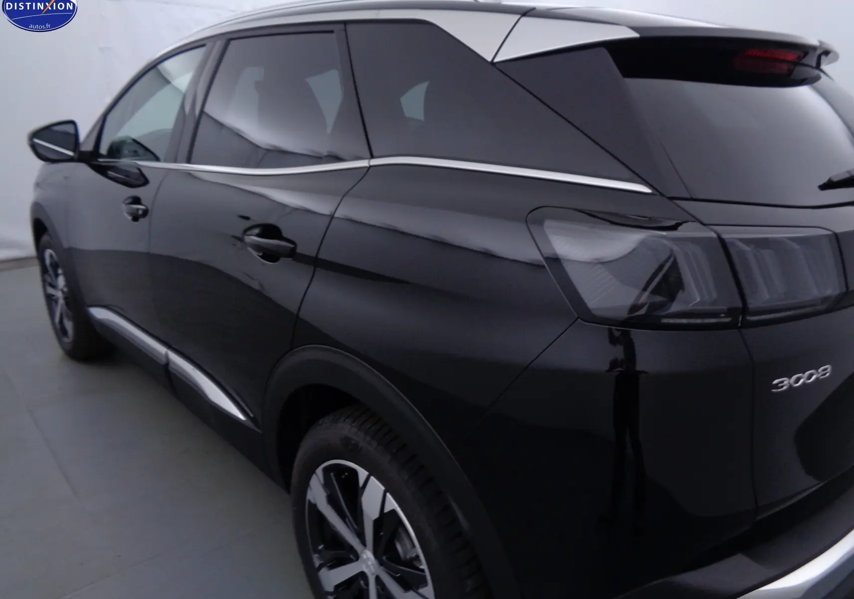 Vue 3/4 arrière côté gauche d’un Peugeot 3008 noir Perla Nera avec feux arrière fumés et jantes bi-ton.
