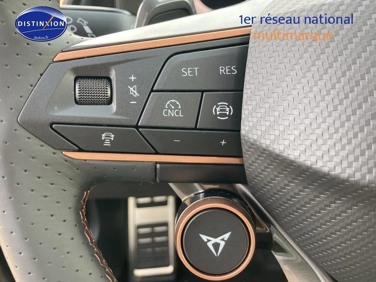 Gros plan sur les commandes multifonctions du volant cuir perforé avec logo CUPRA et surpiqûres cuivre.