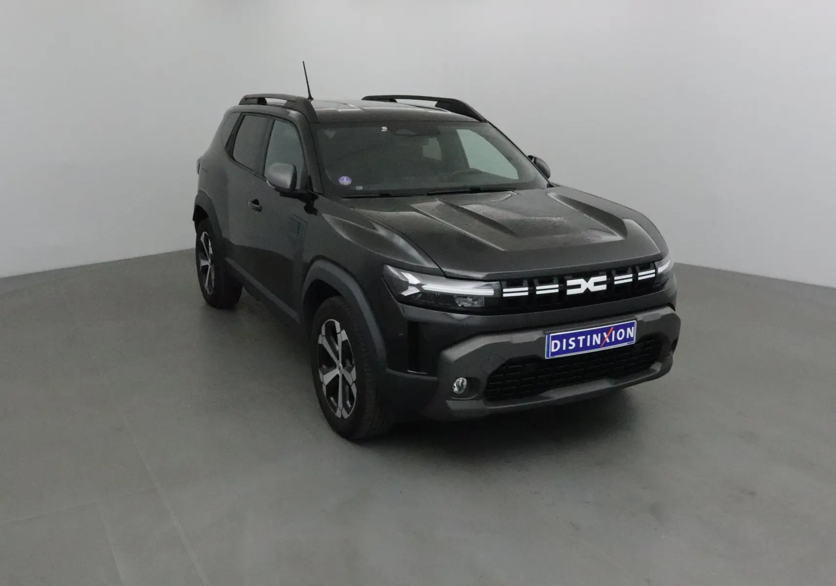 SUV Dacia Duster noir 2024 vu en 3/4 avant droit avec calandre moderne et jantes alliage bicolores.