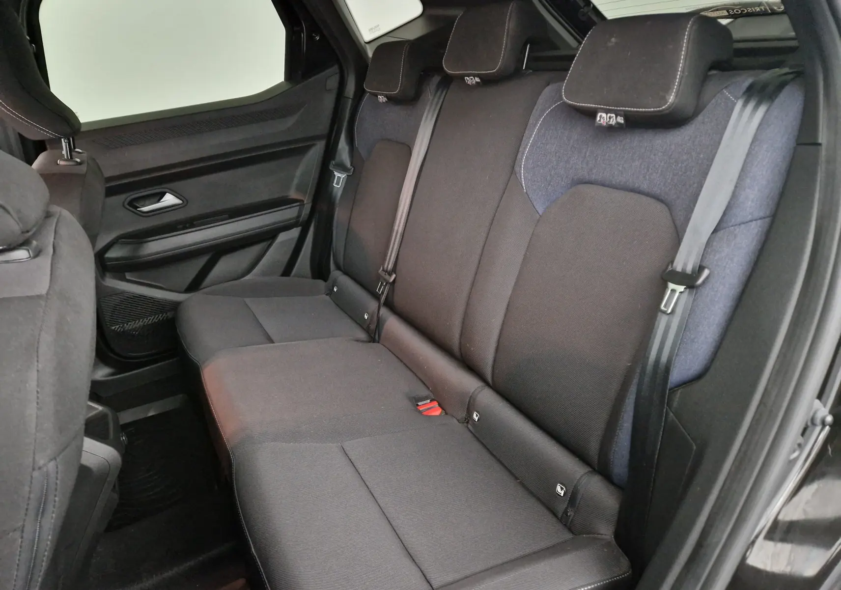 Vue intérieure côté droit des sièges arrière noirs et gris du Dacia Duster 2024 hybride essence.