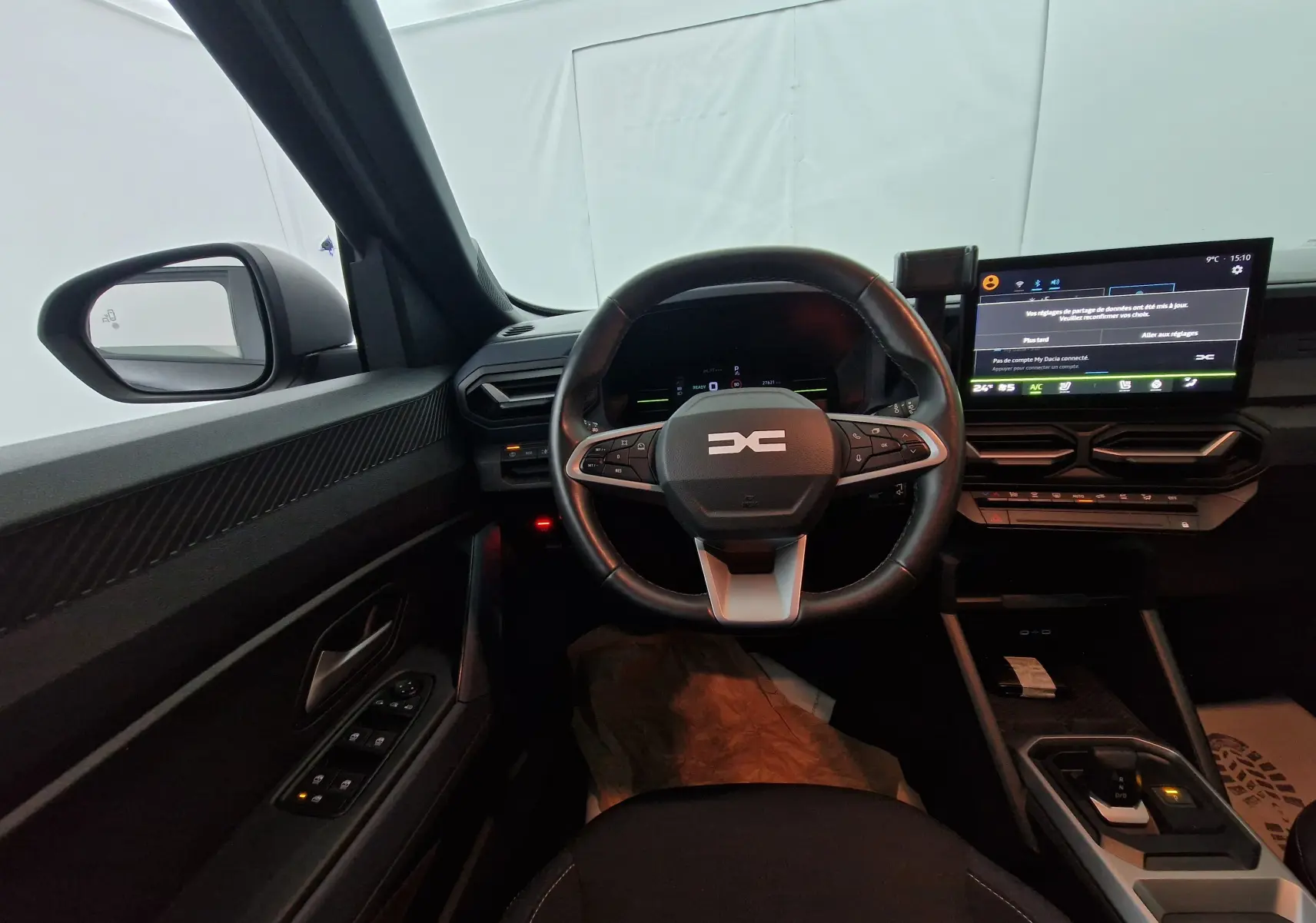 Vue intérieure avant du tableau de bord noir du Dacia Duster 2024 avec volant multifonction et écran tactile large.