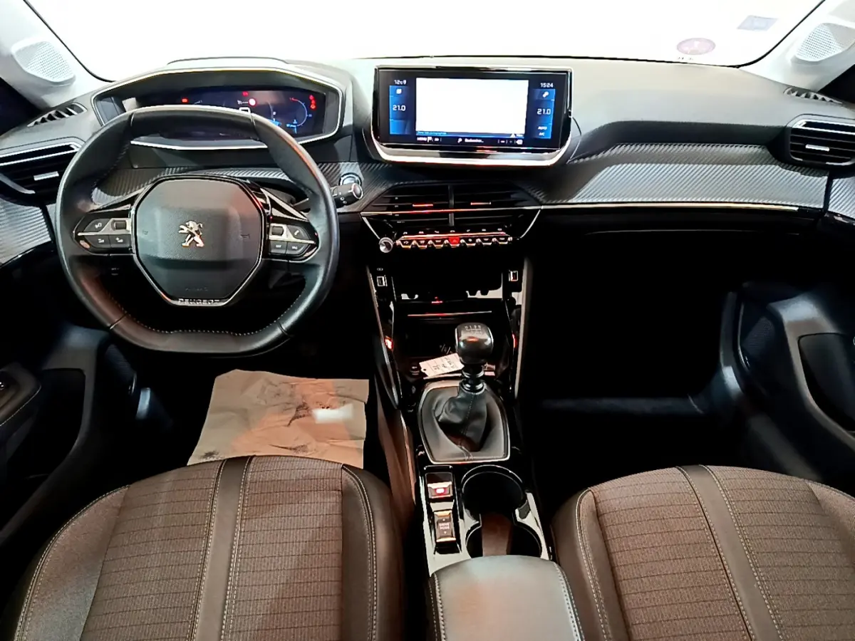 Intérieur de la Peugeot 208 PureTech 100 S&S Allure Business 2020, vue frontale sur tableau de bord et volant cuir noir.