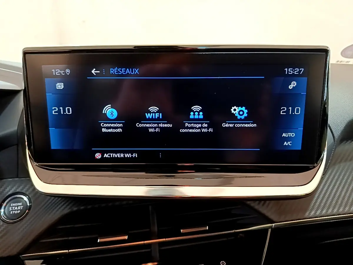 Écran tactile central affichant les options réseau dans l'habitacle d'une Peugeot 208 gris clair, vue frontale rapprochée.