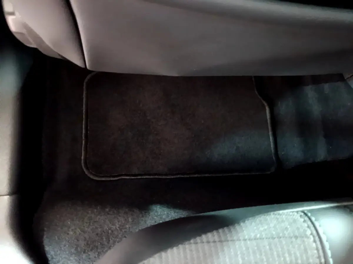 Vue rapprochée du tapis de sol noir sous le siège arrière d'une Peugeot 208 gris clair de 2020