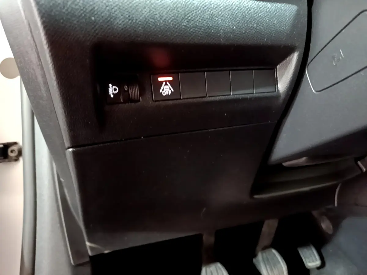 Vue rapprochée du tableau de bord côté gauche de la Peugeot 208 gris clair, montrant les commandes d'éclairage et d'aide à la conduite.
