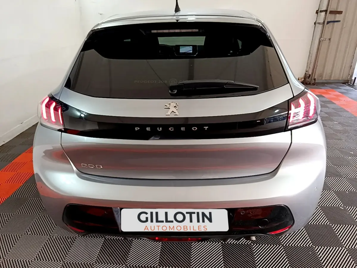 Vue arrière d'une Peugeot 208 gris clair avec feux LED caractéristiques allumés dans un garage.