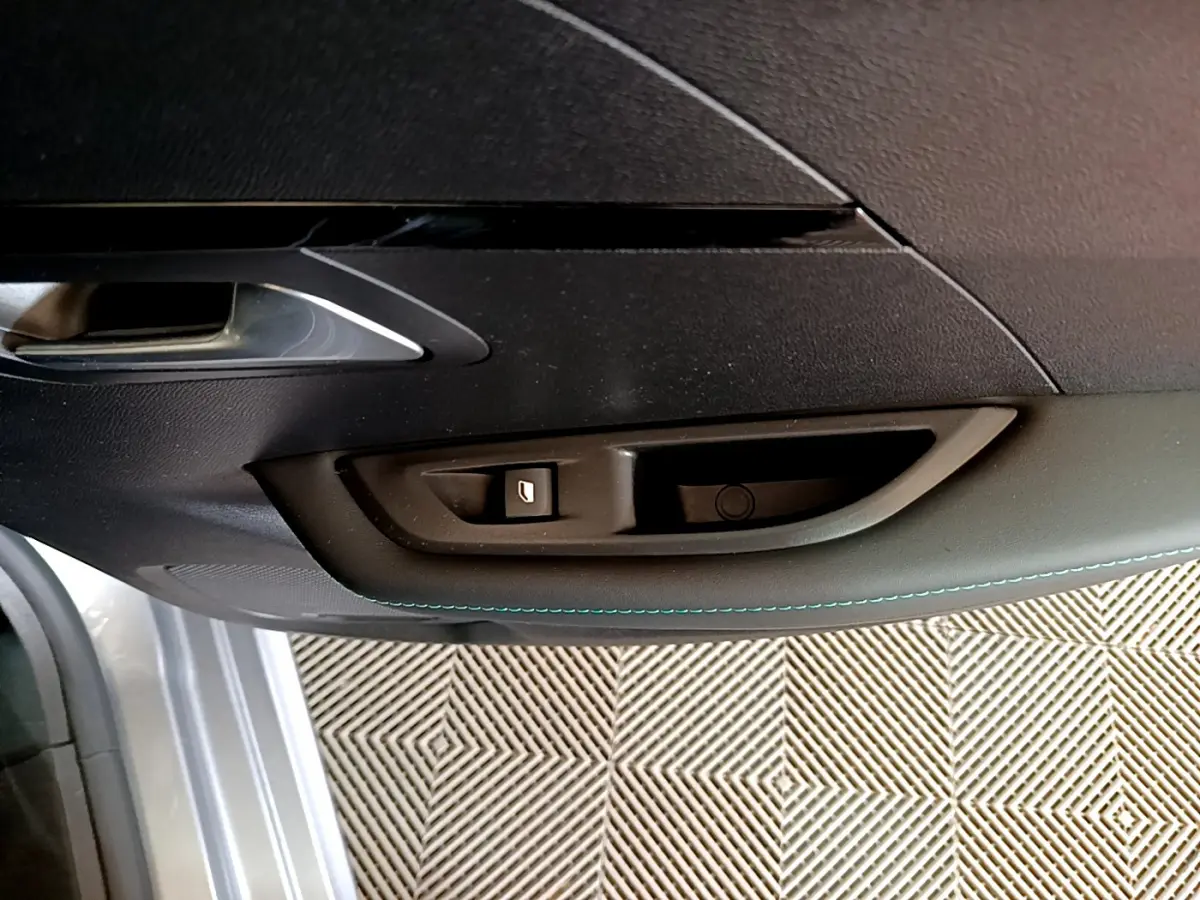 Gros plan sur la poignée intérieure et commande de lève-vitre côté conducteur d'une Peugeot 208 gris clair 2020.