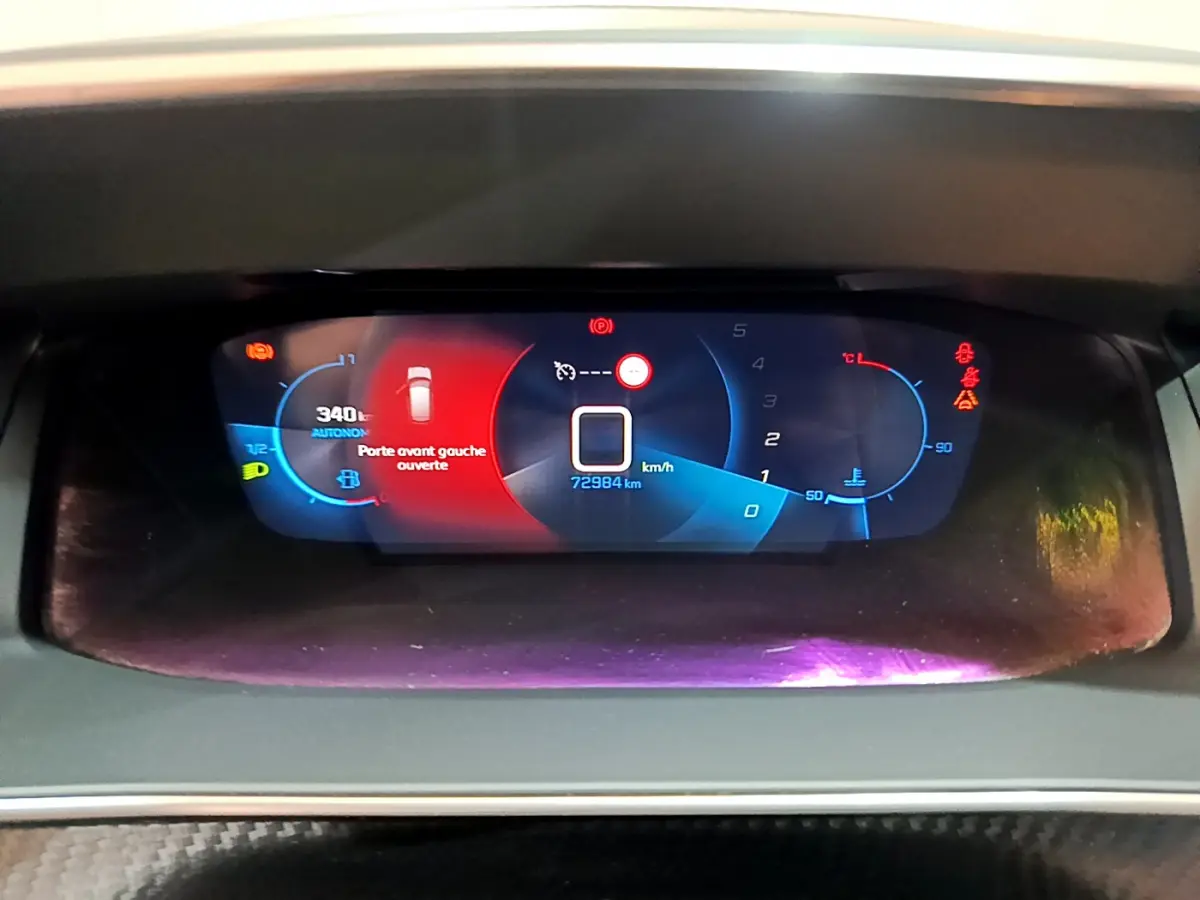 Tableau de bord numérique de Peugeot 208 gris clair affichant la vitesse, autonomie et porte avant gauche ouverte.