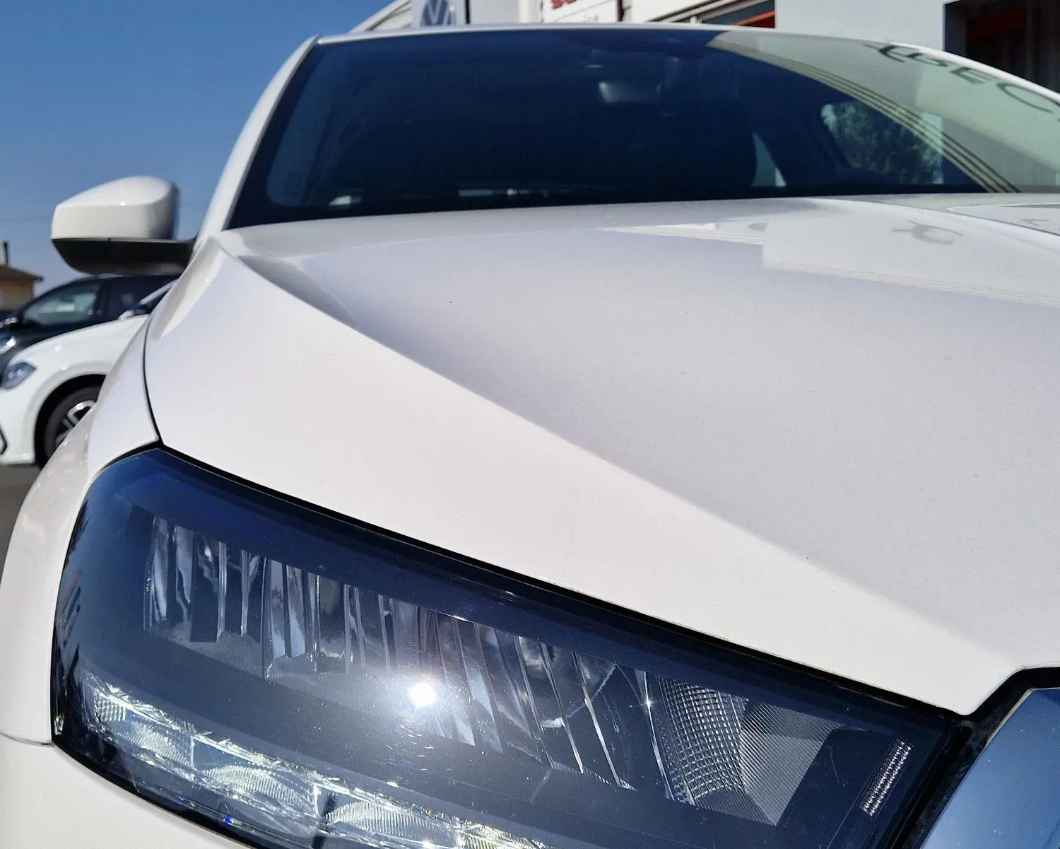 Gros plan sur le phare avant gauche d'une Skoda Fabia berline blanche 2022, avec calandre chromée visible.