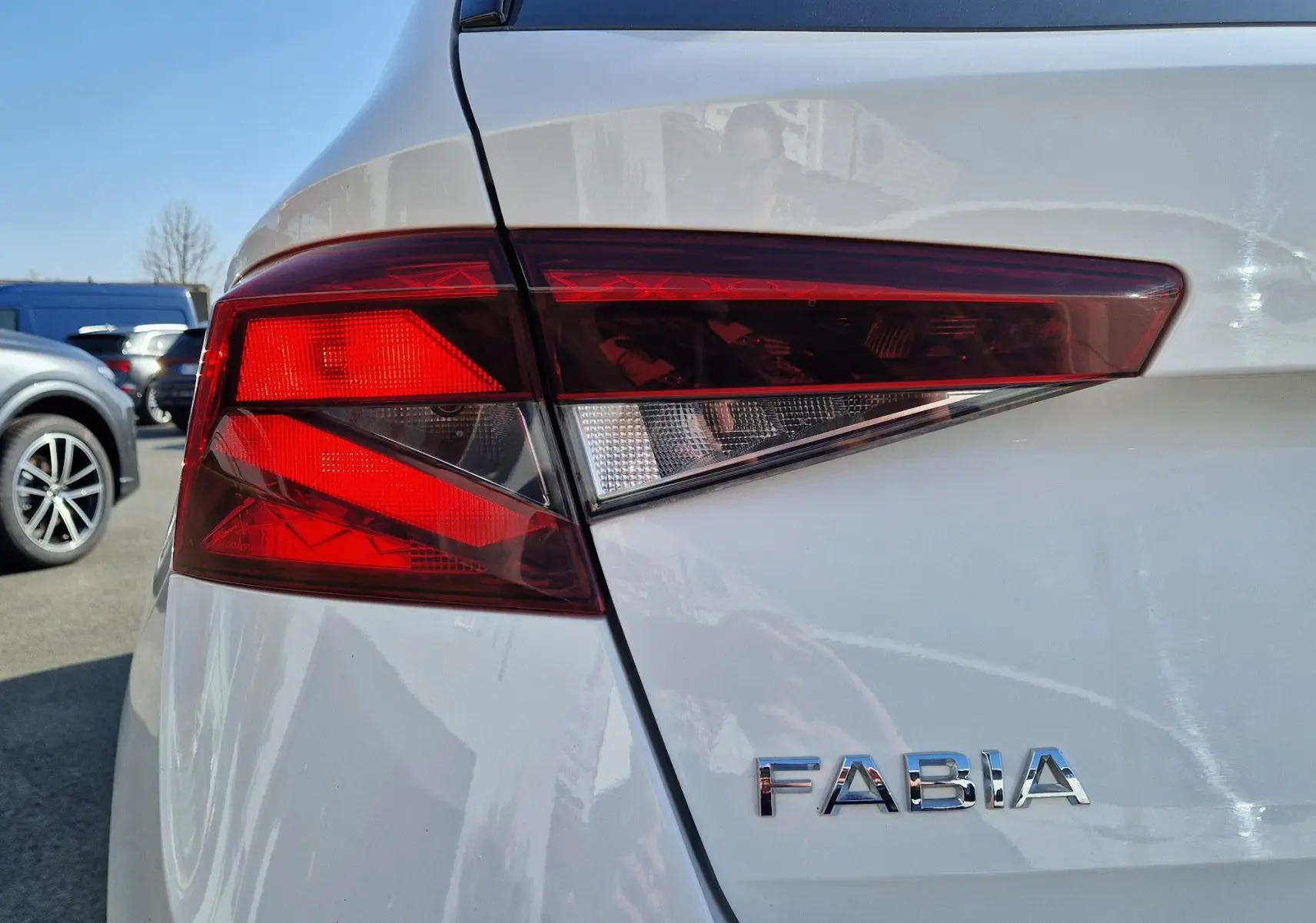 Gros plan sur le feu arrière droit rouge et blanc d'une Skoda Fabia blanche, avec le logo "FABIA" visible sur la carrosserie.