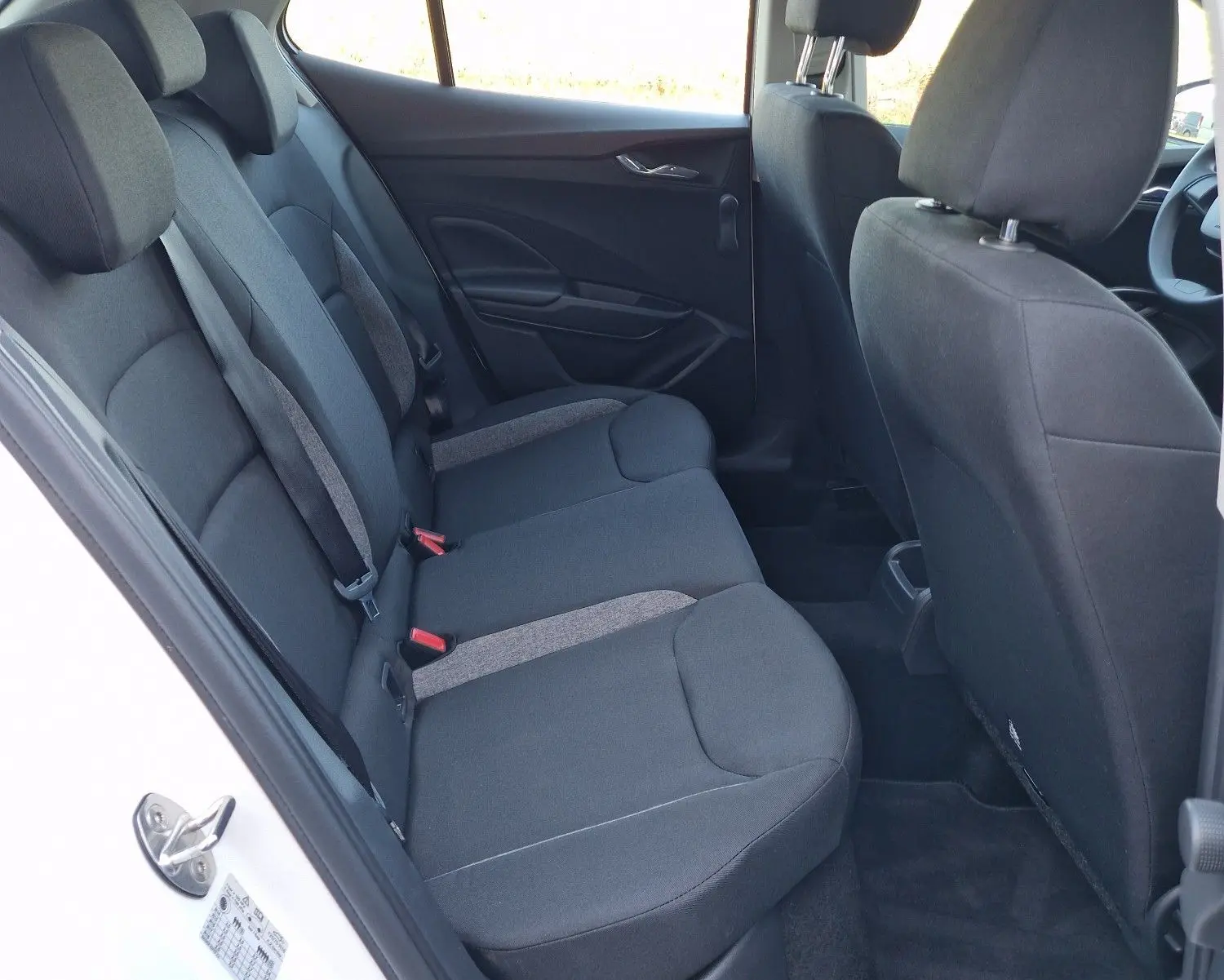 Vue intérieure côté arrière gauche de la Skoda Fabia berline blanche 2022, montrant les sièges arrière en tissu noir.