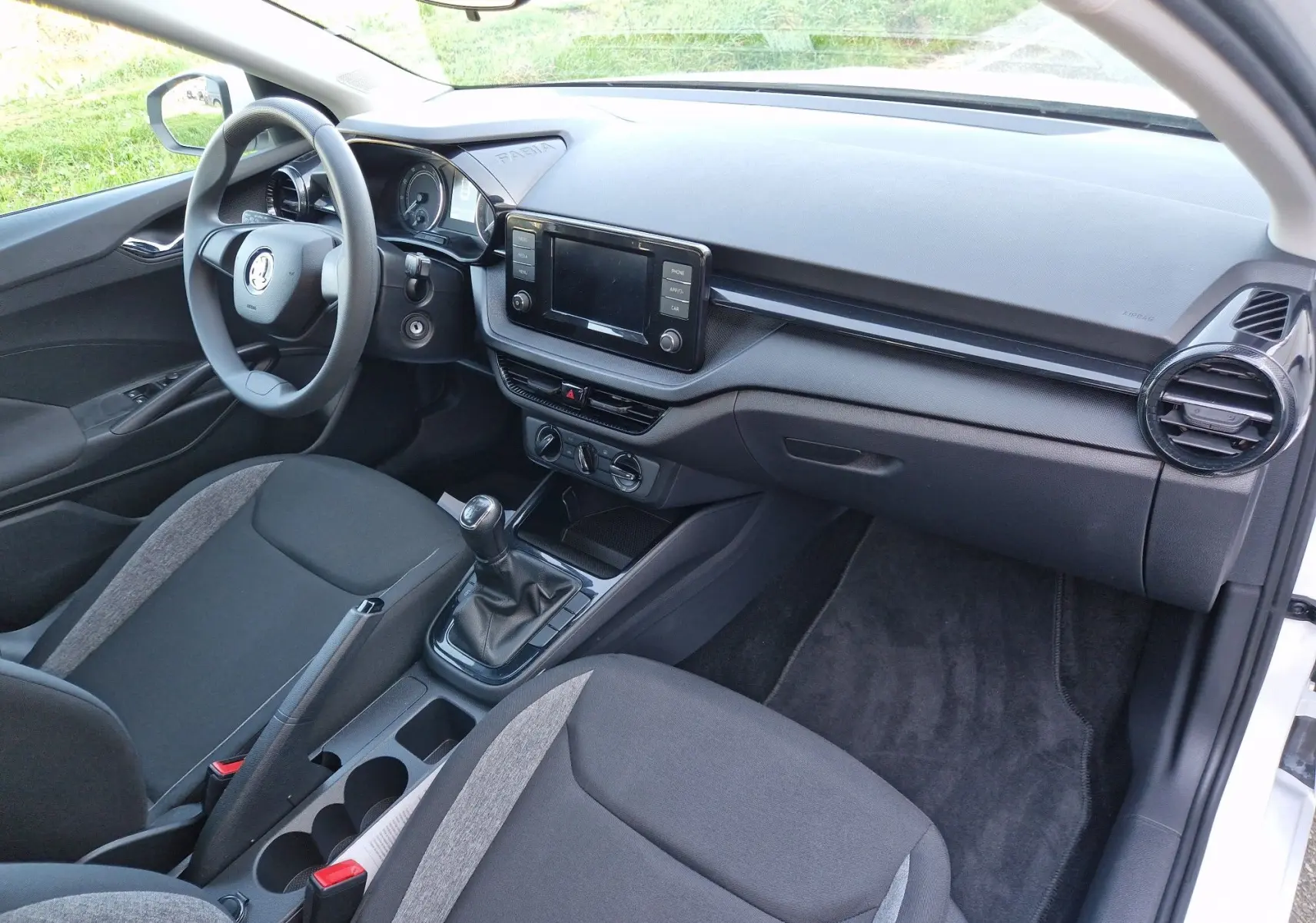 Vue intérieure côté conducteur de la Skoda Fabia Berline Active 2022, avec tableau de bord noir et levier de vitesse manuel.