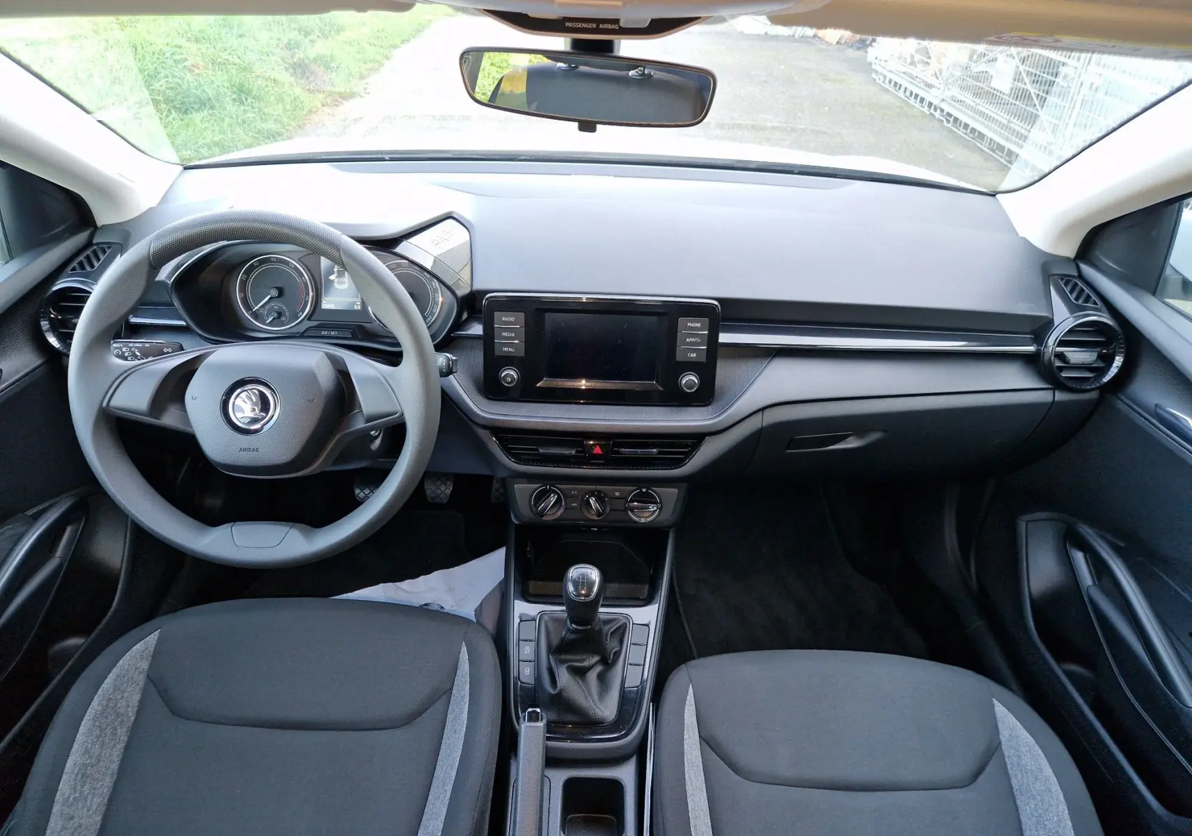 Intérieur de la Skoda Fabia Berline Active 2022 vu de face, tableau de bord noir avec écran central et volant multifonction.