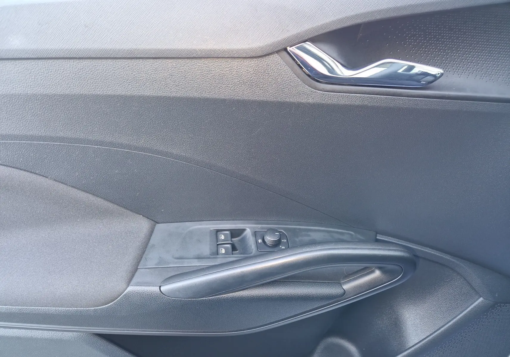 Détail de la porte intérieure côté conducteur de la Skoda Fabia blanche 2022, avec commandes des vitres et rétroviseurs.