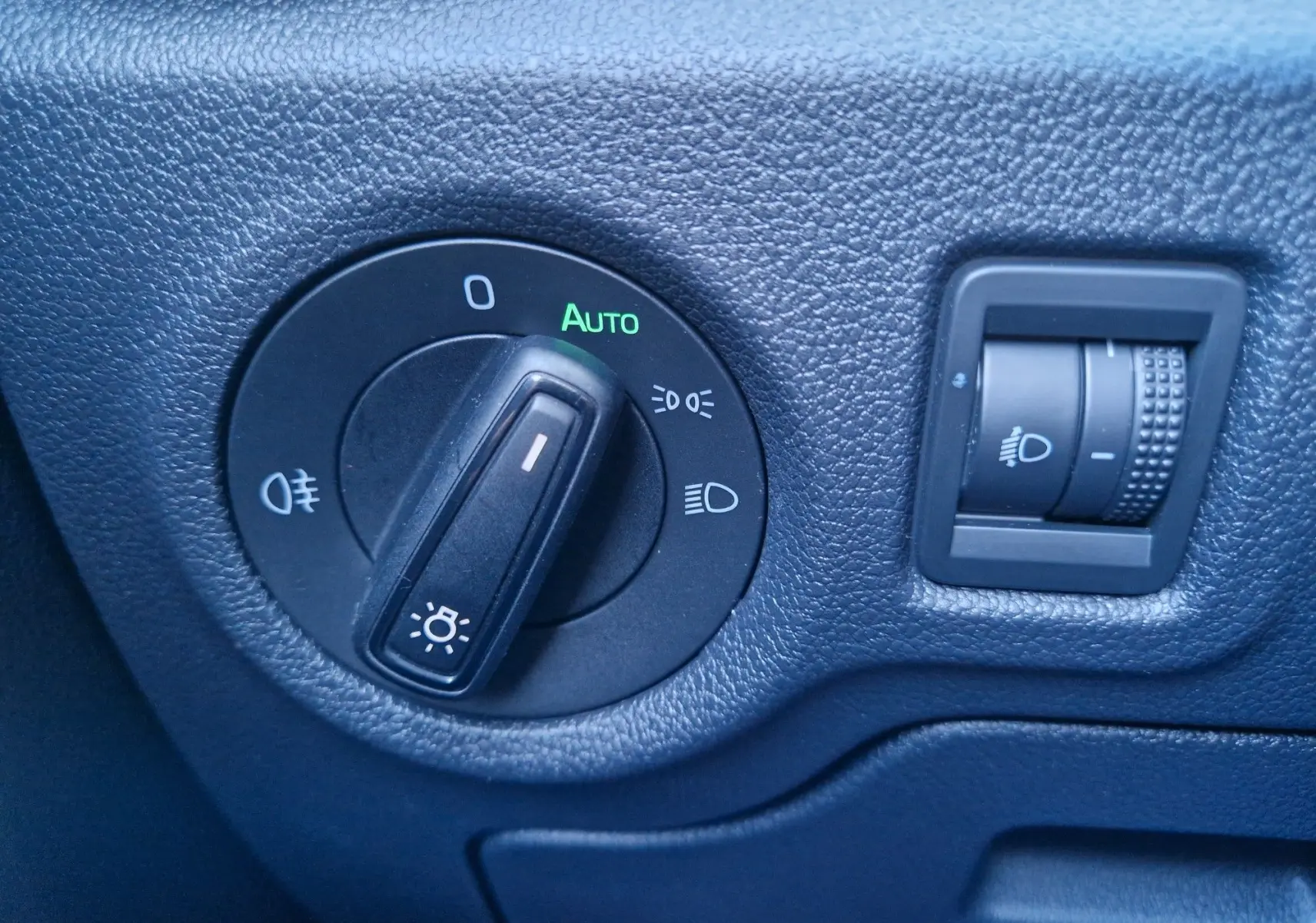 Gros plan sur les commandes d’éclairage noir mat du tableau de bord d’une Skoda Fabia blanche de 2022.