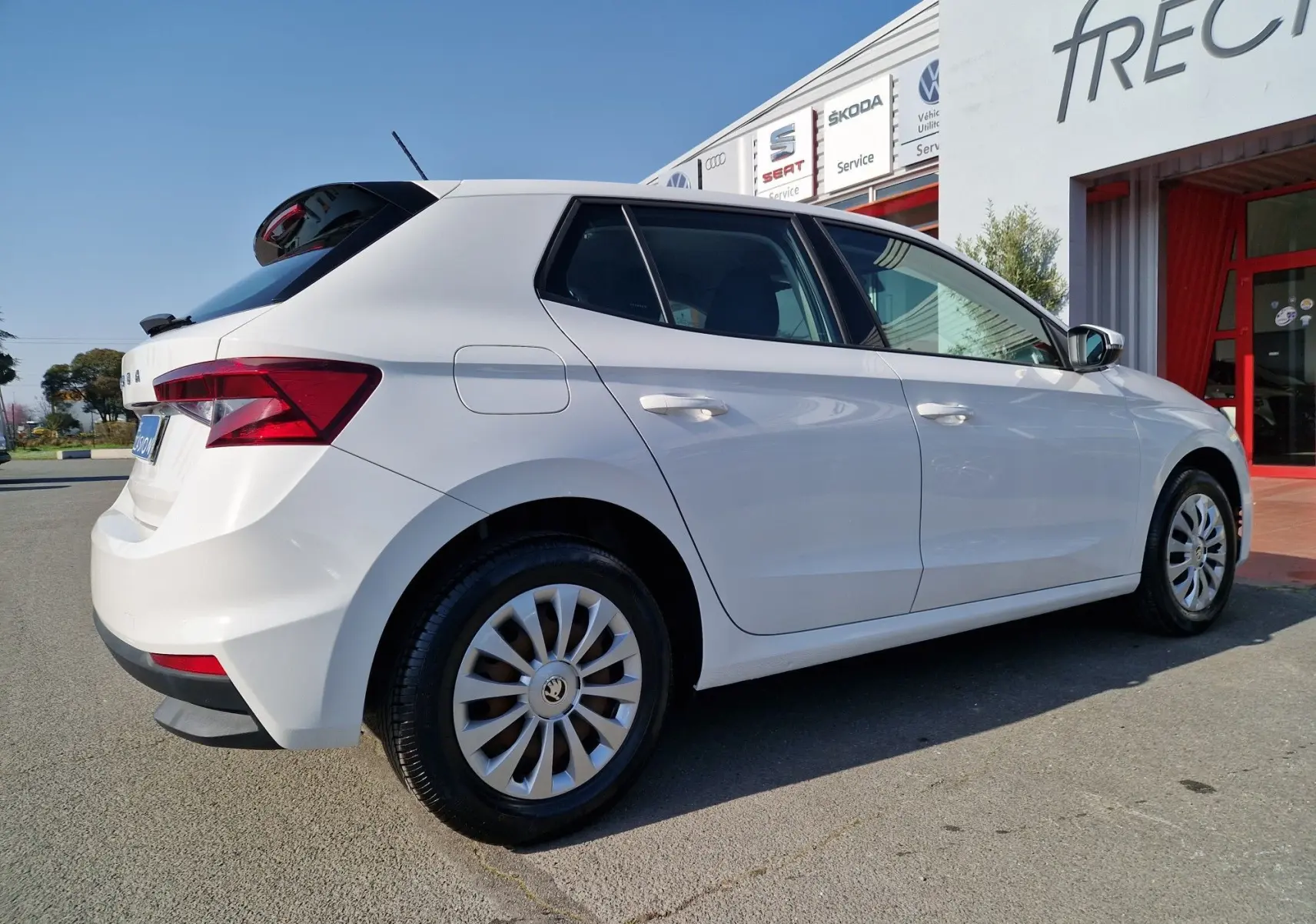 Vue 3/4 arrière droite d'une Skoda Fabia Berline Active blanche 2022, avec jantes acier et feux arrière distinctifs.