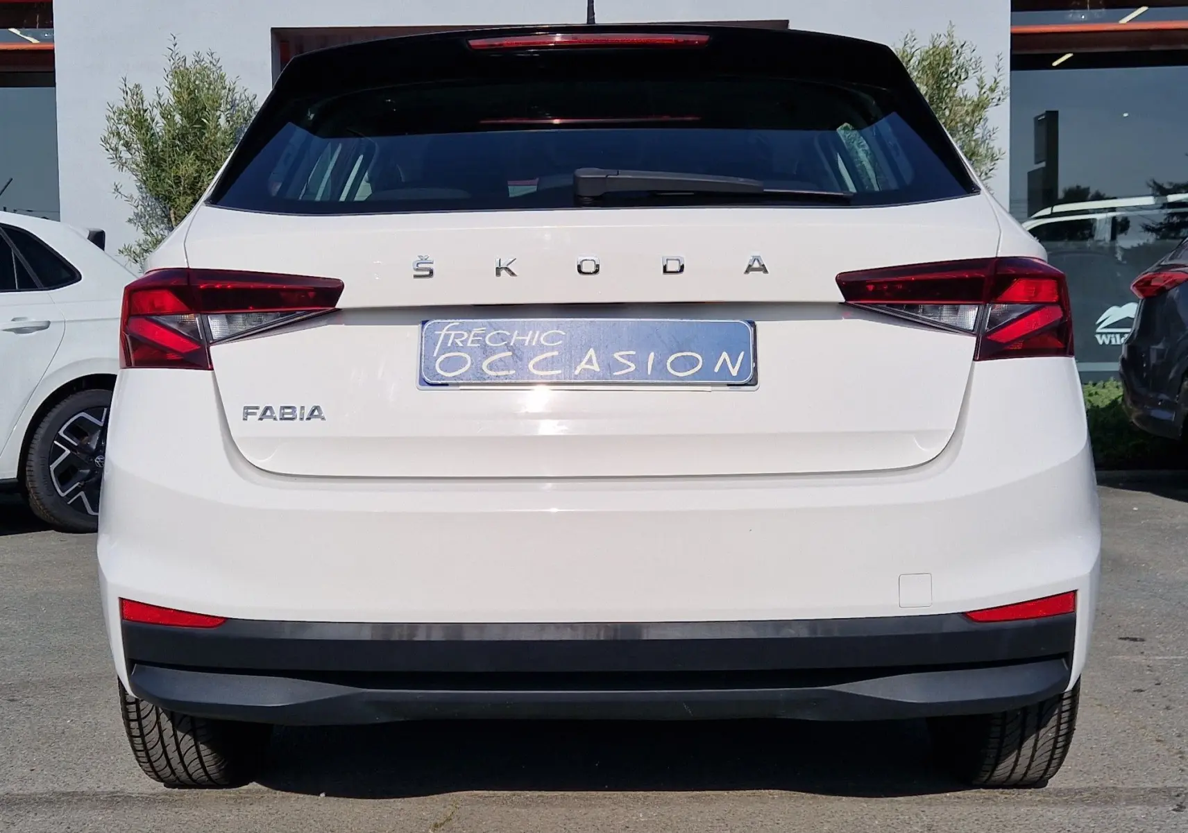 Vue arrière d'une Skoda Fabia berline blanche 2022 avec feux arrière rouges et plaque d'occasion bleue.