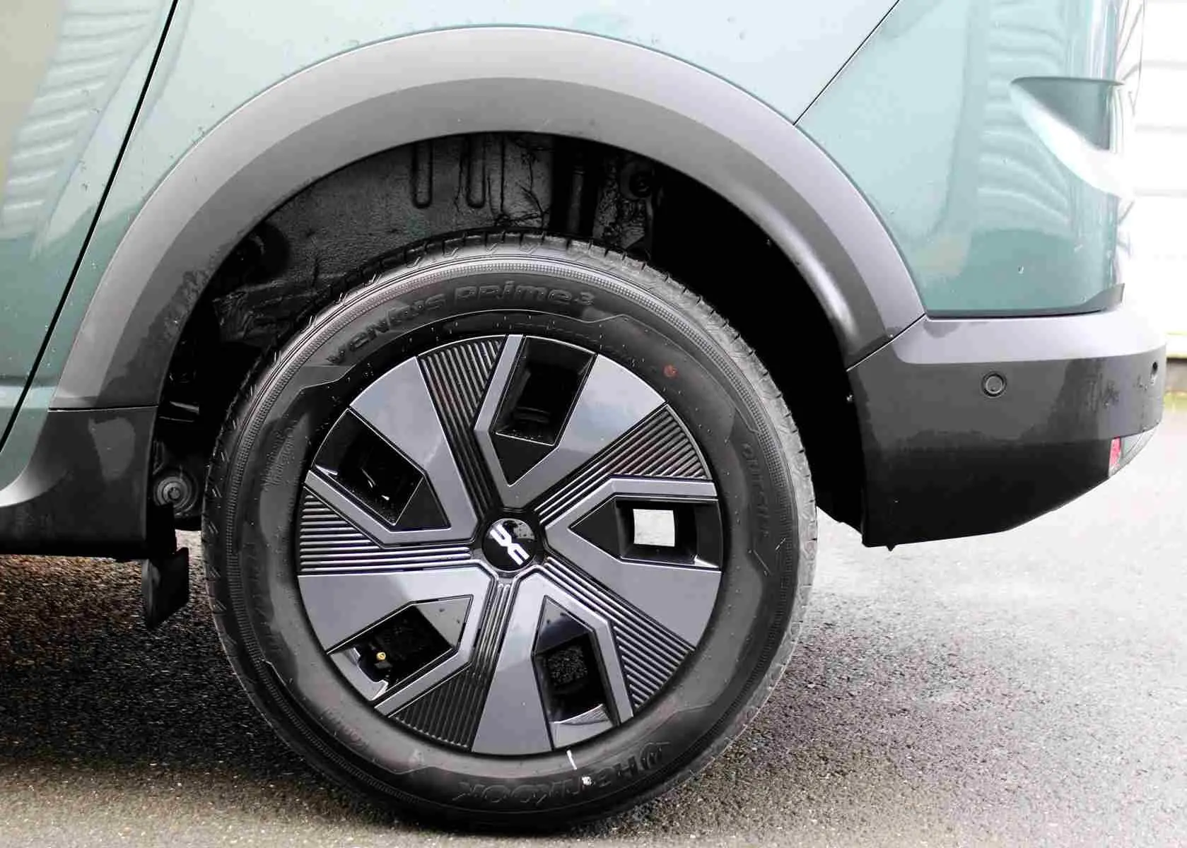 Gros plan sur la roue arrière droite du Dacia Jogger vert cèdre métal, avec jante au design géométrique moderne.