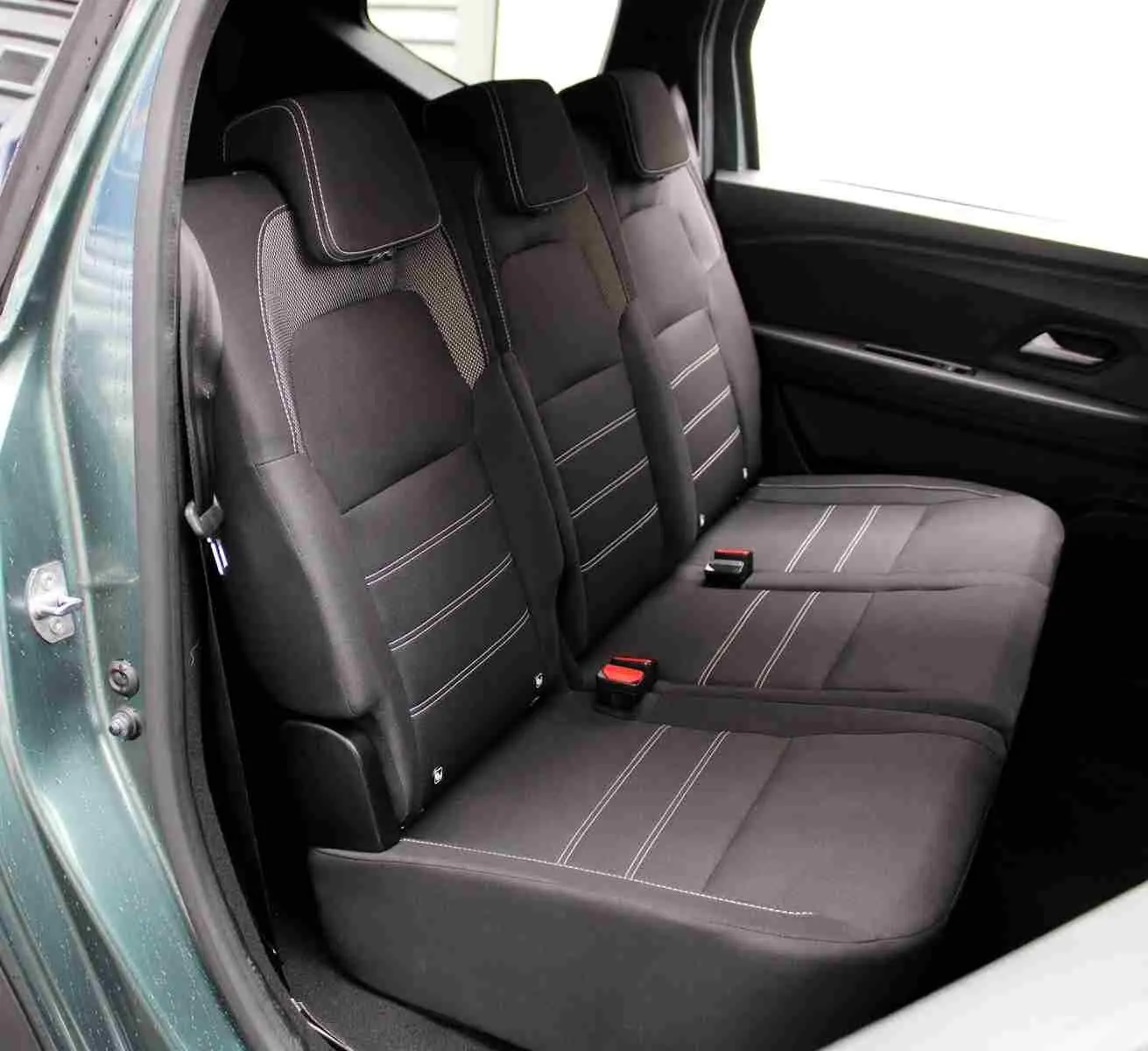 Vue intérieure côté gauche sur la banquette arrière noire avec surpiqûres blanches du Dacia Jogger vert cèdre 2025.