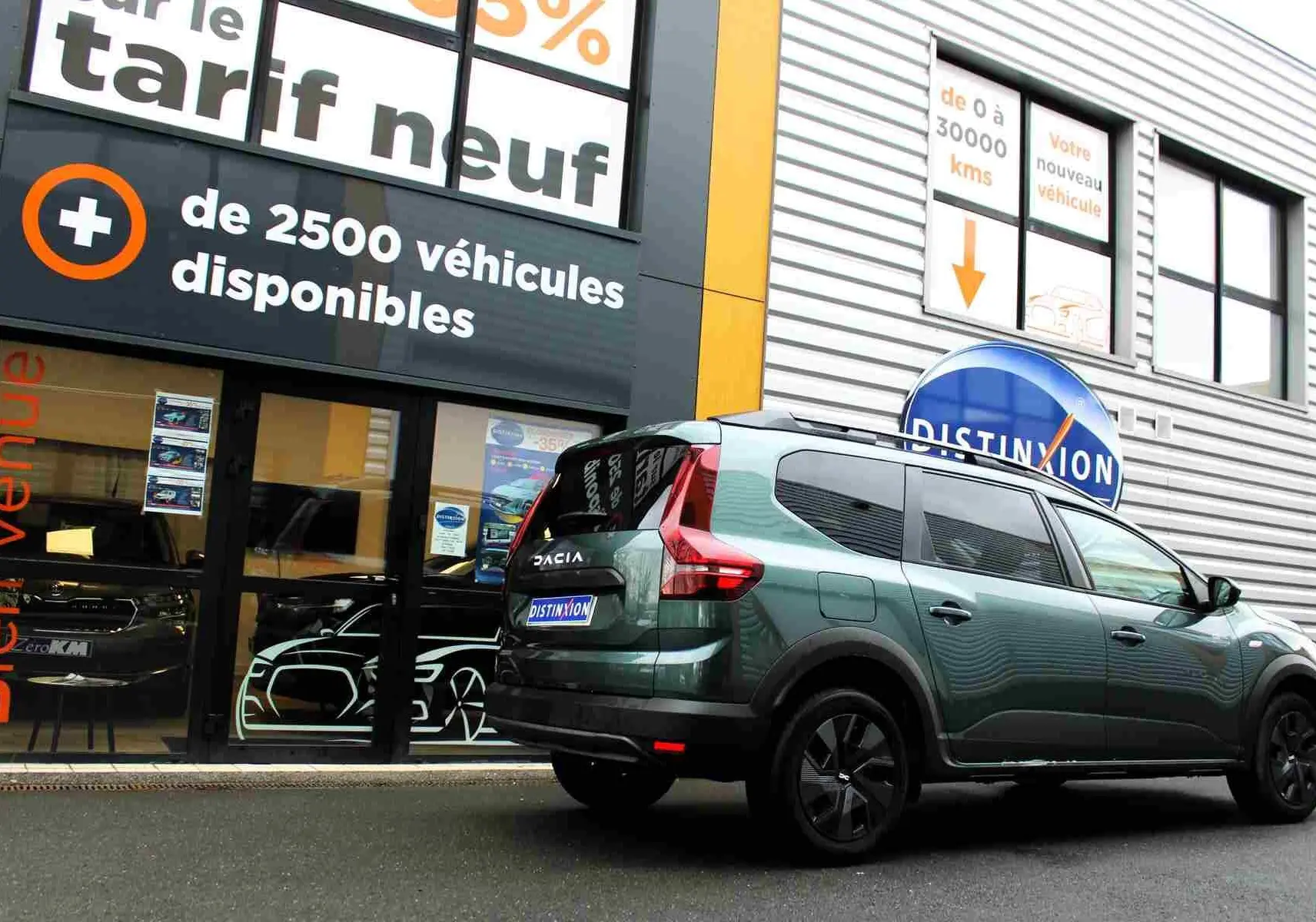 Vue 3/4 arrière droite d'un Dacia Jogger vert cèdre métallisé avec vitres teintées, garé devant un showroom.