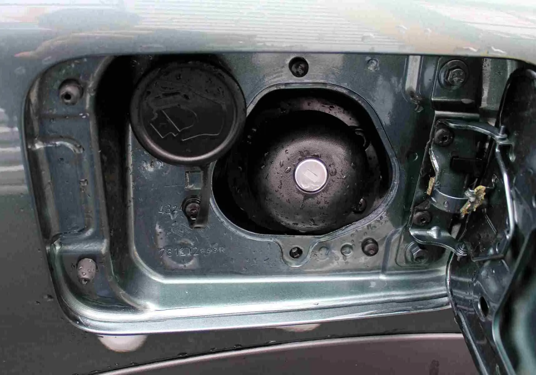 Gros plan sur la trappe à carburant ouverte du Dacia Jogger vert cèdre métal, montrant les bouchons essence et GPL.